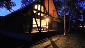 Een modern houten huis met grote ramen en een veranda.