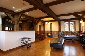 A spacious living area with a fireplace, wooden beams, a dining table, and a sofa. - Bliss Cottage Sakura (Kutchan)