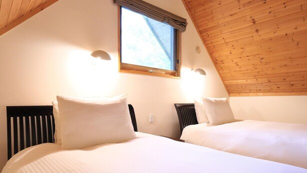 Een slaapkamer met twee bedden, een houten plafond en een raam met gordijnen.