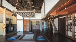A spacious room with a wooden floor, a ceiling with exposed beams, and a hanging light fixture. - Glamping Villa Sameya Awaji (Sumoto)