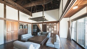 A spacious living room with a large wooden coffee table, grey sofas, and a wooden ceiling with exposed beams. - Glamping Villa Sameya Awaji (Sumoto)