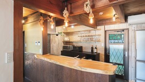 A kitchen with a wooden island, hanging rope lights, and a view through a frosted glass door. - Glamping Villa Sameya Awaji (Sumoto)