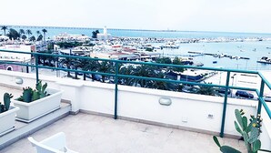 A balcony with a view of a marina and boats, a railing, and potted plants. - Casa Manfredi Homes&villas (Manfredonia)