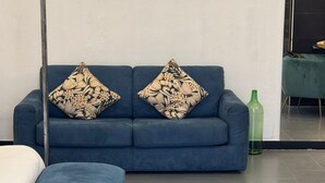 Un saló modern amb un sofà blau, un otomà a joc i un quadre abstracte gran a la paret.