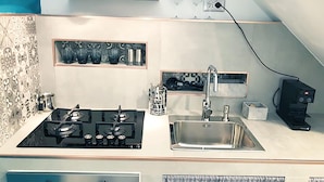 A compact kitchen with a gas stove, a sink, and a coffee machine. - Casa Manfredi Homes&villas (Manfredonia)