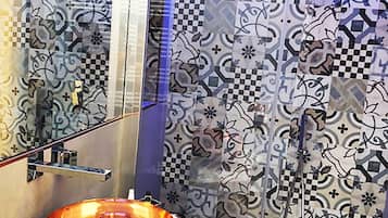 Une salle de bain avec des carreaux décorés, un lavabo en forme de bol en verre et un porte-serviettes.