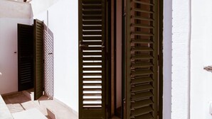 A narrow alleyway with two open doors, one with horizontal blinds and the other with vertical blinds. - Casa Manfredi Homes&villas (Manfredonia)