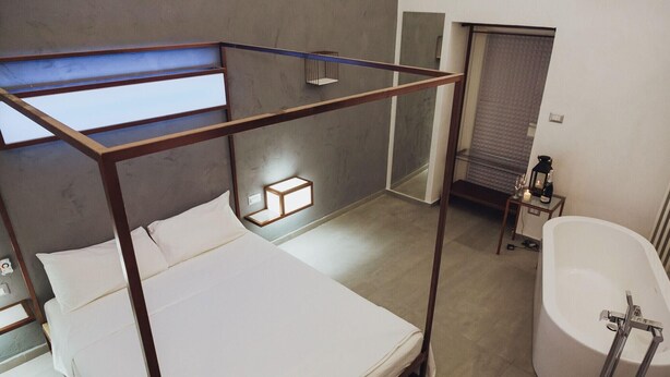 A bunk bed with a wooden frame, a small bedside table with a bottle and glass, and a bathroom with a bathtub and a towel rack. - Casa Manfredi Homes&villas (Manfredonia)