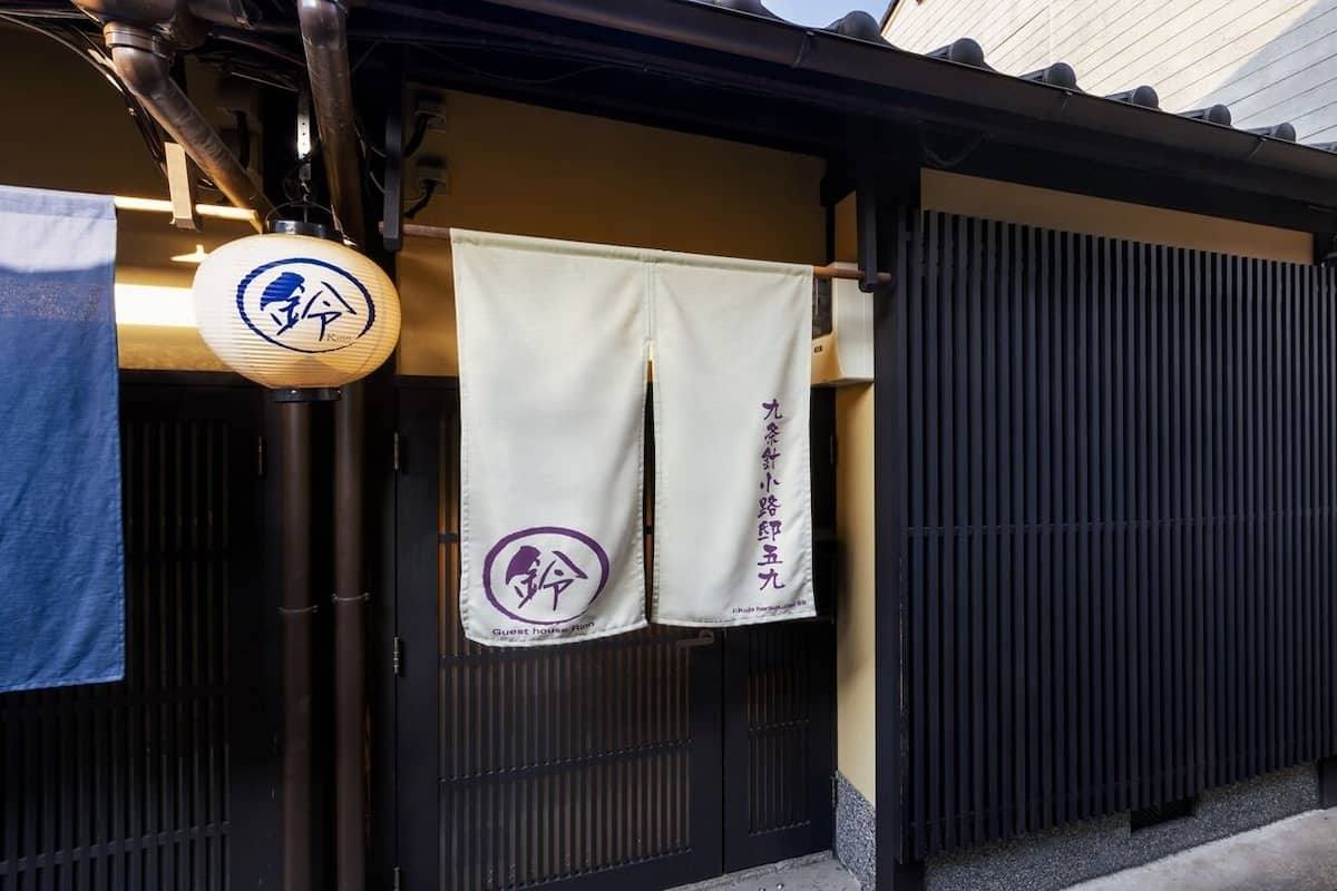 Ein traditionelles japanisches Gebäude mit einer schwarzen Schiebetür, einem blauen Handtuch und einem Laternen