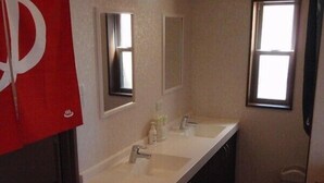 Un baño con dos lavamanos, un espejo y una ventana.