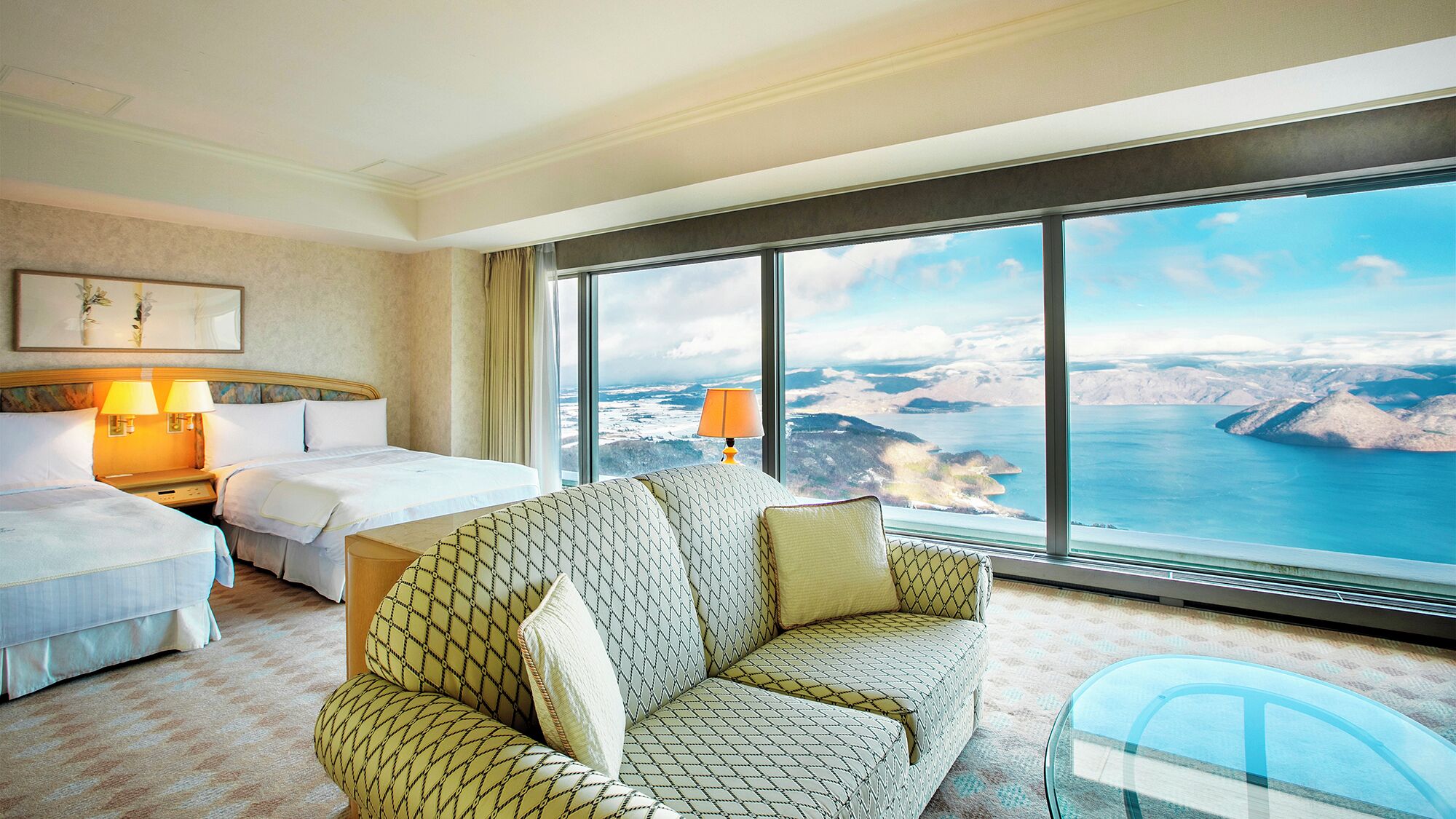 Ein Hotelzimmer mit großem Fenster, zwei Betten, einer Couch und einer Lampe.