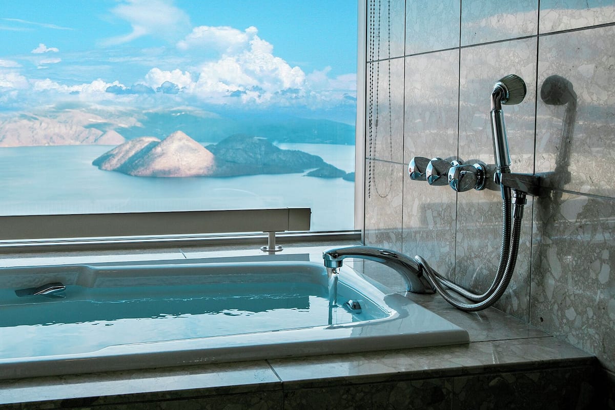 Une salle de bain avec une baignoire, une douche et une vue sur un lac et des montagnes.