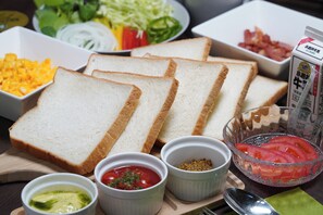 A table with sliced bread, various condiments, and a bowl of tomatoes. - Forest Cottage Oshu (Oshu)