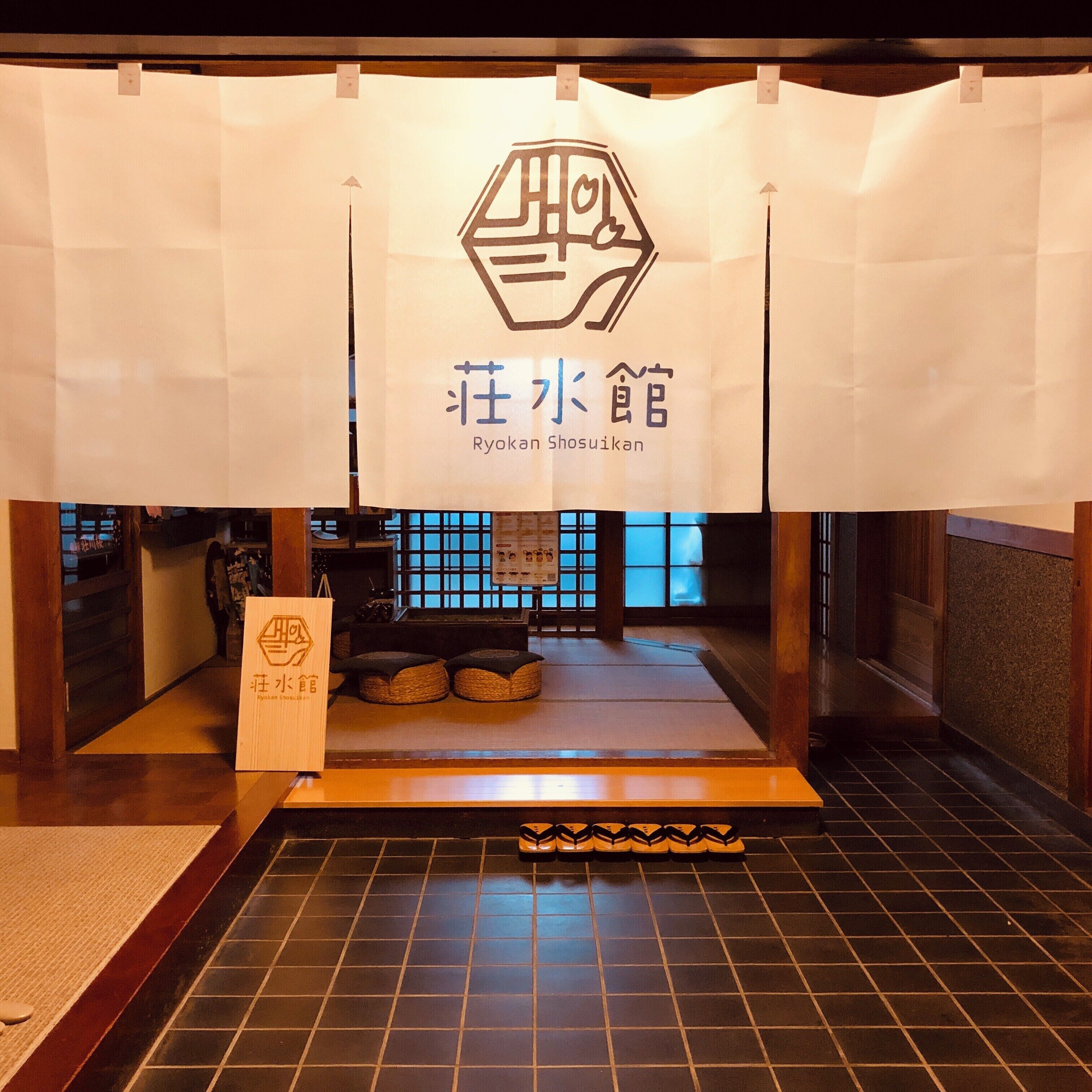 A traditional Japanese Ryokan with tatami flooring, a low wooden counter, and a signboard with Japanese characters.