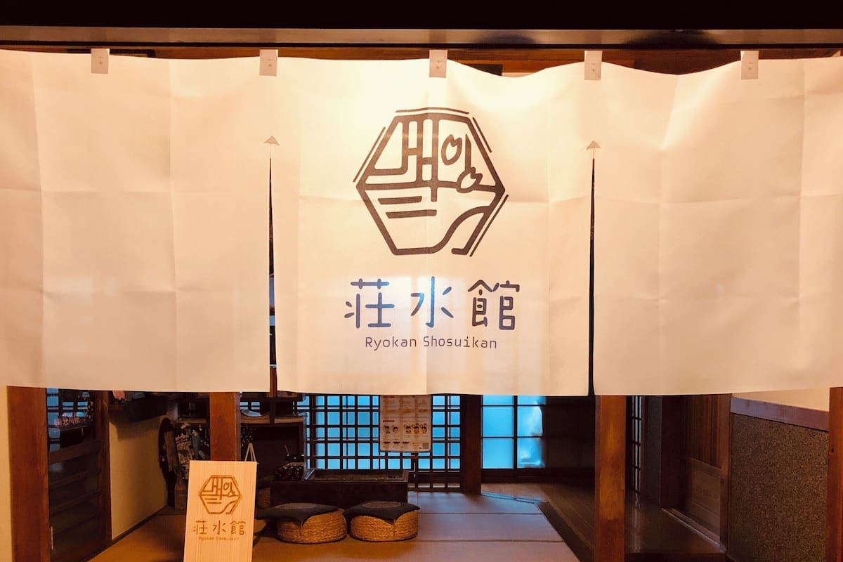 A traditional Japanese Ryokan with tatami flooring, a low wooden counter, and a signboard with Japanese characters.