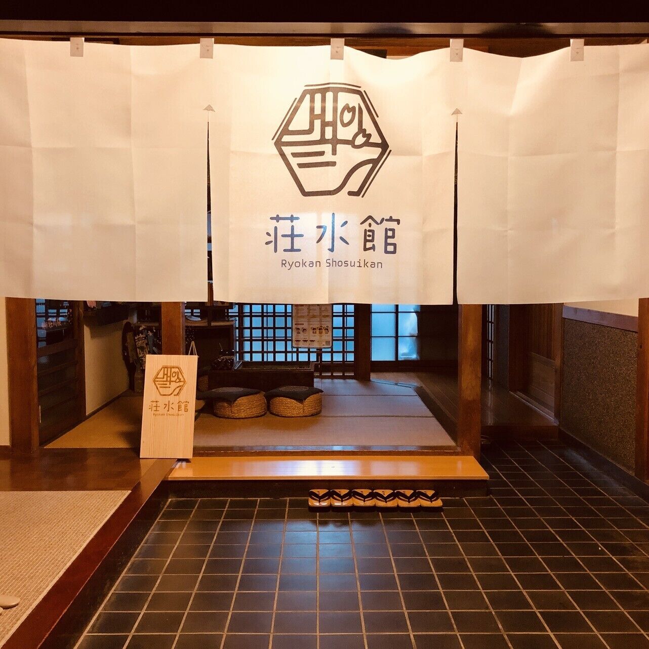 A traditional Japanese Ryokan with tatami mats, a low wooden table, and a sign with Japanese characters.