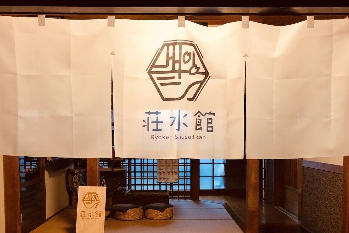 A traditional Japanese Ryokan with tatami mats, a low wooden table, and a sign with Japanese characters.