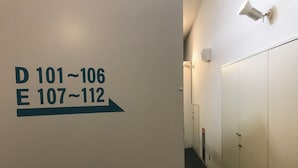 A hallway with directional signs indicating room numbers D 101-106 and E 107-112. - Geto Kogen Ski Resort (Kitakami)