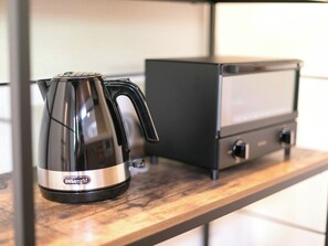 A Delonghi coffee maker on a wooden countertop next to a black appliance, possibly a toaster or microwave. - Sejour Oyama Annex 3rd Building (Daisen)