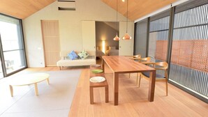 Un intérieur moderne avec une table à manger en bois, des chaises, un canapé et une grande fenêtre offrant une vue dégagée.