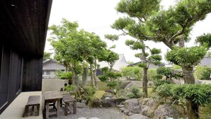 Un jardin japonais traditionnel avec un banc en bois, des rochers et divers arbres.