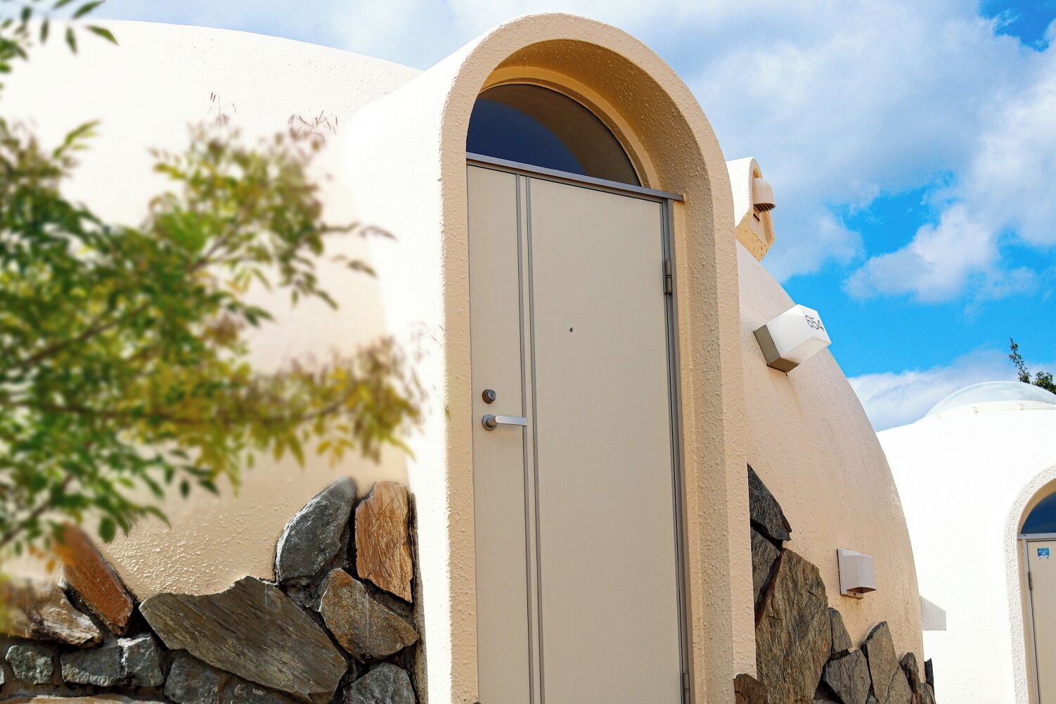 A building with a beige exterior, a stone wall, and a door.