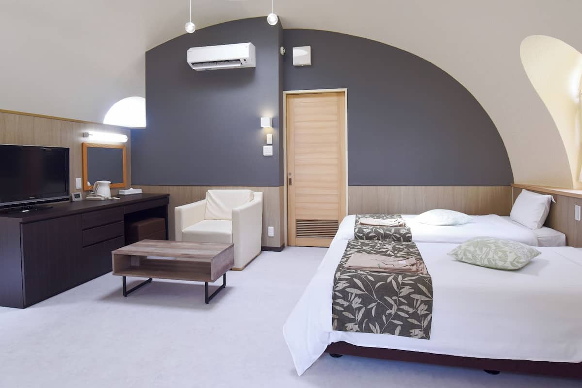 Ein modernes Hotelzimmer mit Bett, Schreibtisch, Stuhl, Fernseher und einem großen Spiegel.