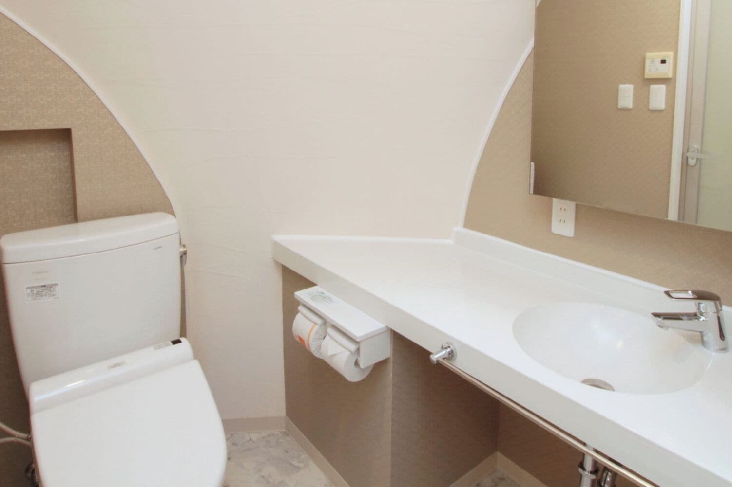 A bathroom with a toilet, a sink, and a towel dispenser.