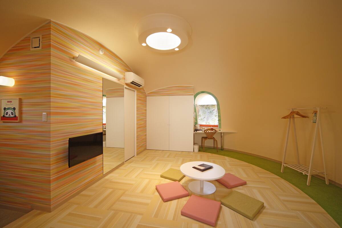 A cozy room with a herringbone-patterned floor, a round table with a book, and a window with a view of the outdoors.