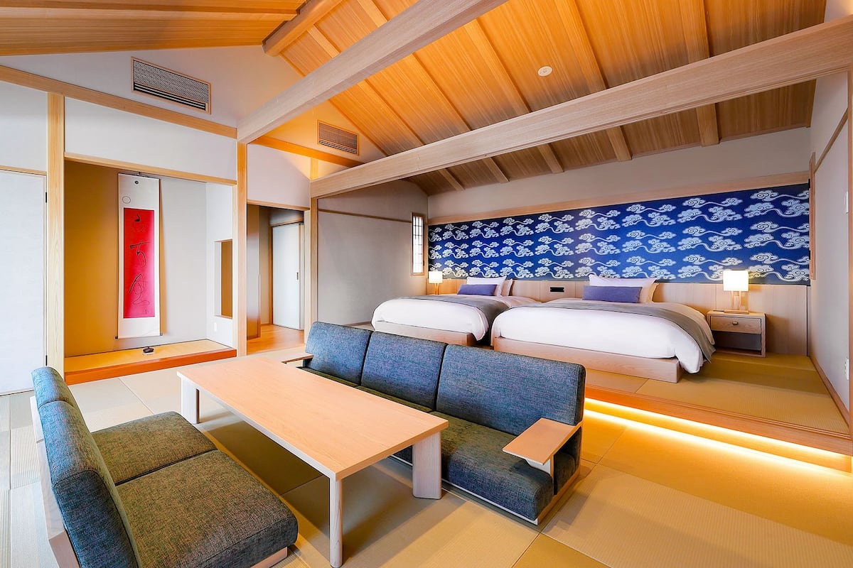 Une chambre d’hôtel comprenant un lit, deux tables de chevet, un canapé, une table et une armoire.