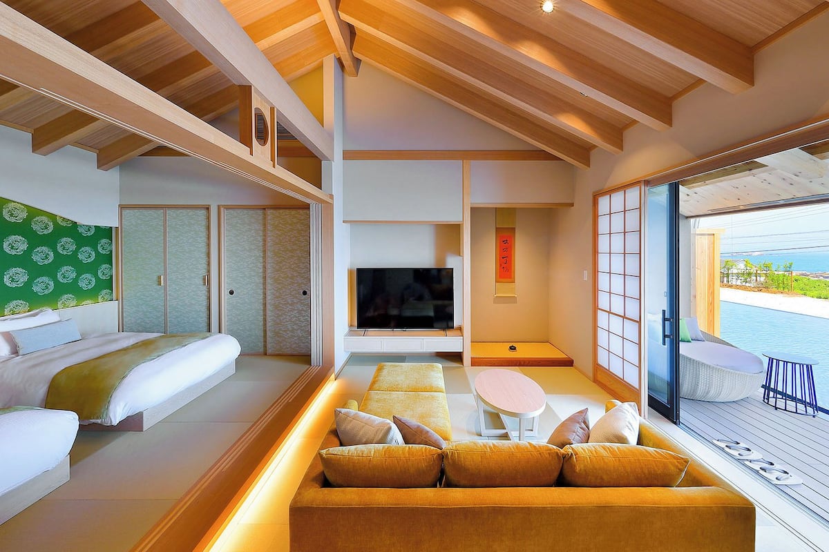 Une chambre d’hôtel moderne équipée d’un lit, d’un canapé, d’une télévision et offrant une vue sur la mer.