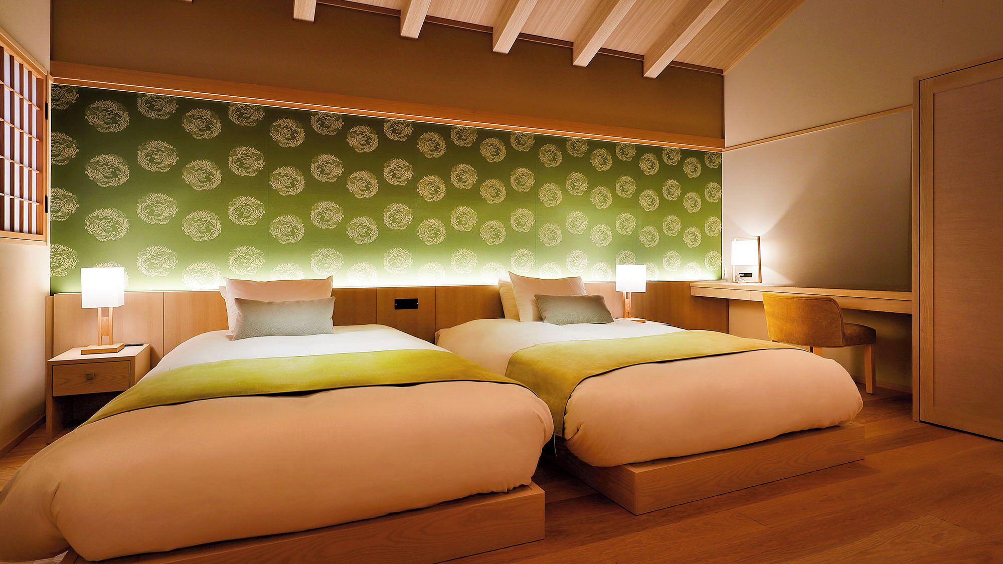 Une chambre d’hôtel avec deux lits, un bureau, une chaise, une table de chevet et une lampe.