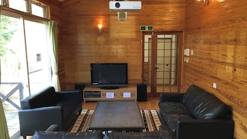 Interior de madeira com televisão, assentos e uma porta sinalizada com a placa de saída.