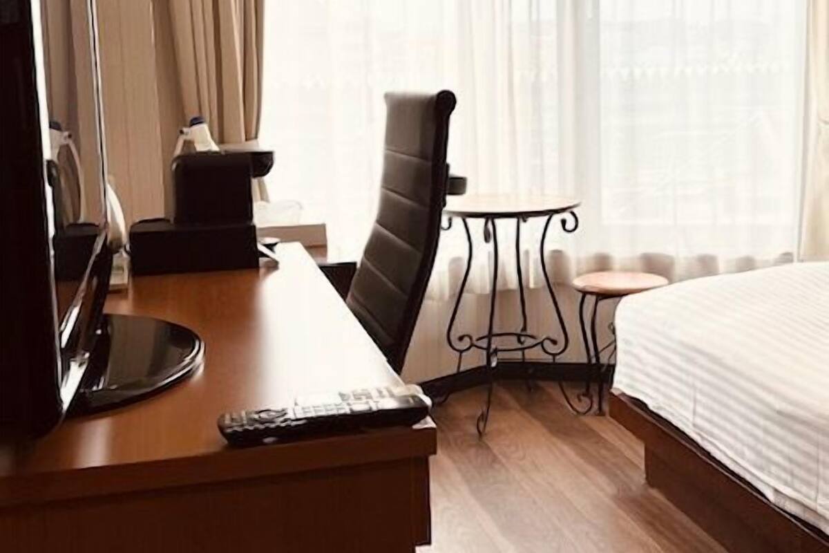 A hotel room with a desk, chair, bed, and a small table.