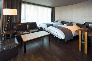 A hotel room with a sofa, two beds, a desk, and a lamp. - Oita Onsen Business Resort Kyuan (Oita)