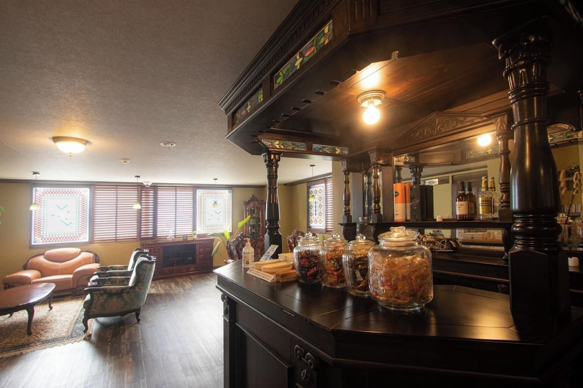Uma área de bar com mobiliário de madeira, um balcão com potes e um espelho grande.