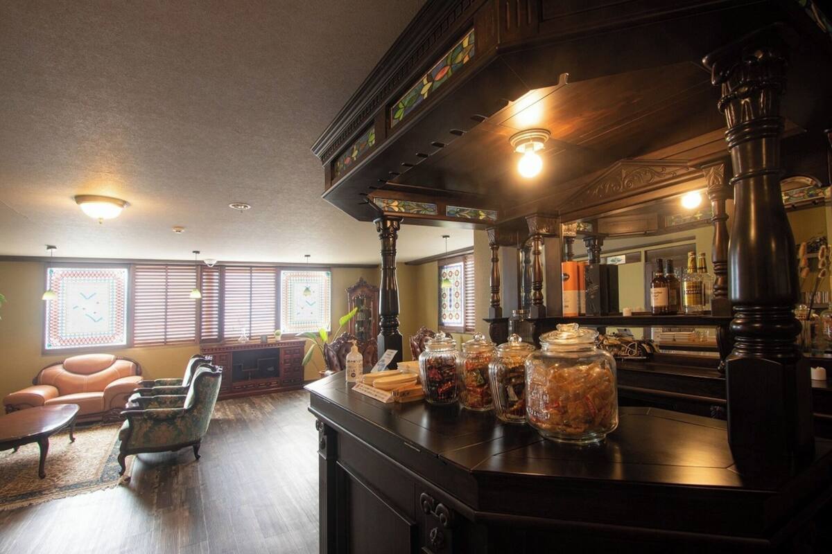 Een bar met houten meubels, een toonbank met potten en een grote spiegel.