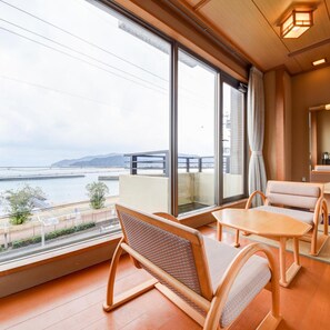 A room with large windows, a wooden floor, and a view of a body of water and mountains. - Shikisainoyado Hanatsubaki (Obama)