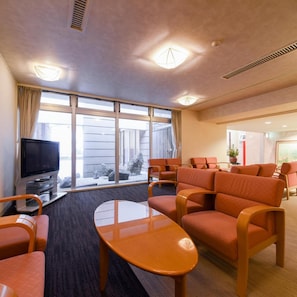 Habitación de hotel con televisor, zona de estar y amplios ventanales.
