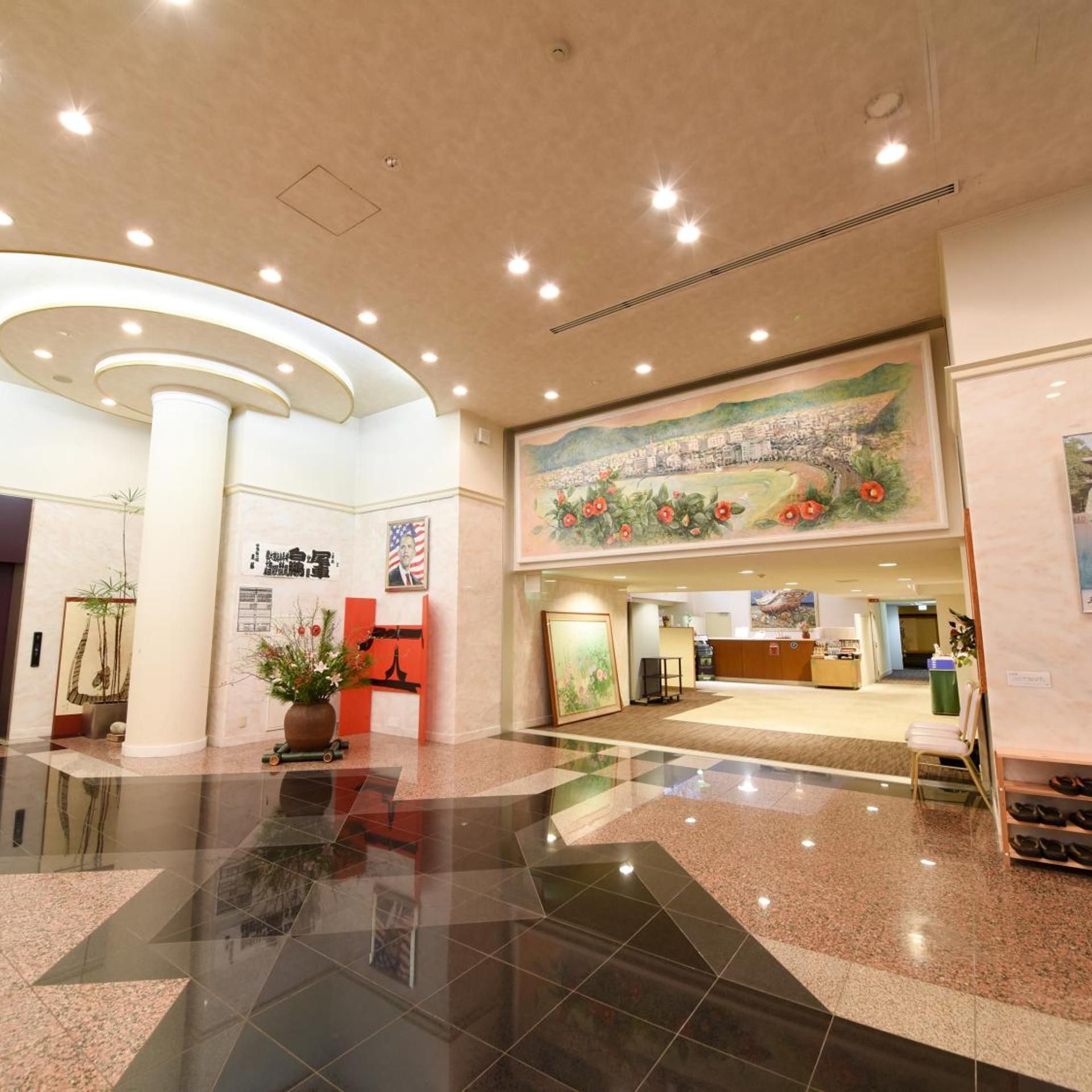 A hotel lobby with a reception desk, a large mural, and a check-in counter.