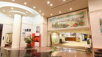 A hotel lobby with a reception desk, a large mural, and a check-in counter.