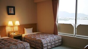Ein Hotelzimmer mit zwei Betten, einem Nachttisch, einem Tisch und einem Fenster mit Blick.
