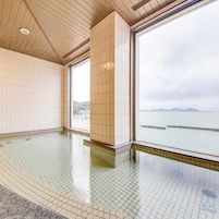 Una piscina interior amplia con paredes de azulejos y vistas despejadas al mar gracias a grandes ventanales.
