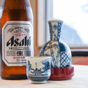 Eine Flasche Asahi Super Dry Bier, eine Keramikvase und eine kleine Tasse auf einem Tisch.