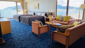 A hotel room with a bed, two sofas, a coffee table, and a desk.