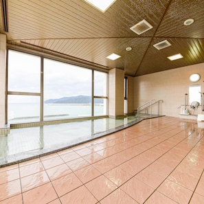 Ein großzügiger, überdachter Pool mit Panoramafenstern, die Blick auf das Meer und die Berge bieten.