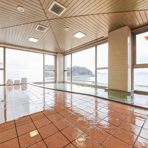 Una piscina interior con techo de madera y ventanas amplias.