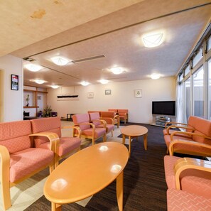 Une pièce avec des canapés, des fauteuils, un téléviseur et une fenêtre.
