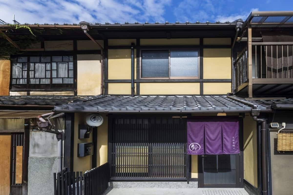 Ein traditionelles japanisches Gebäude mit einem Ziegeldach, einer Holztür und einem kleinen Vorbereich.