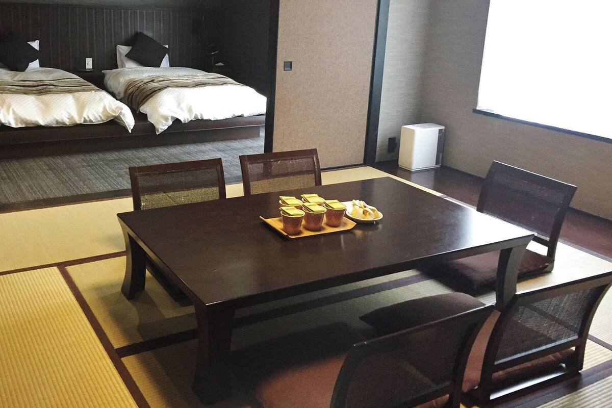 Een hotelkamer met een bed, een eettafel met stoelen en uitzicht op zee.